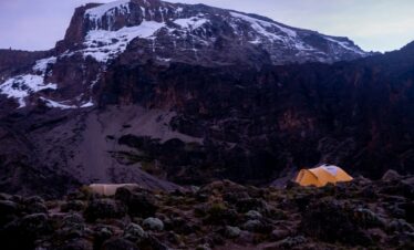 a tent in a rocky area with snow on the top