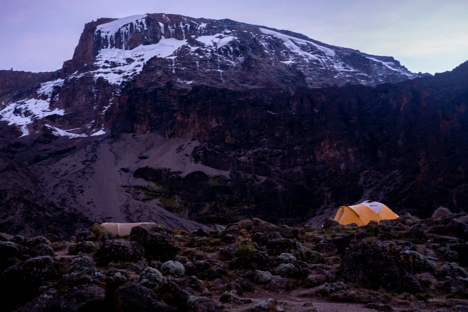 a tent in a rocky area with snow on the top