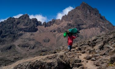 a person with a green backpack walking up a mountain