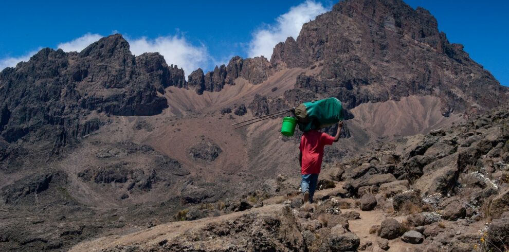 a person with a green backpack walking up a mountain